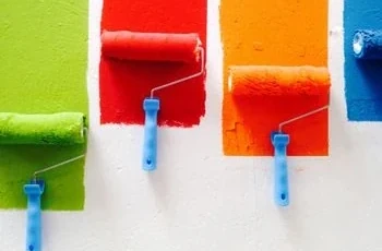 Drei Farbrollen streichen Wand in Grün, Rot und Orange für Malerarbeiten und Renovierung.